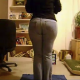 A woman pees in her jeans as we view her from behind.